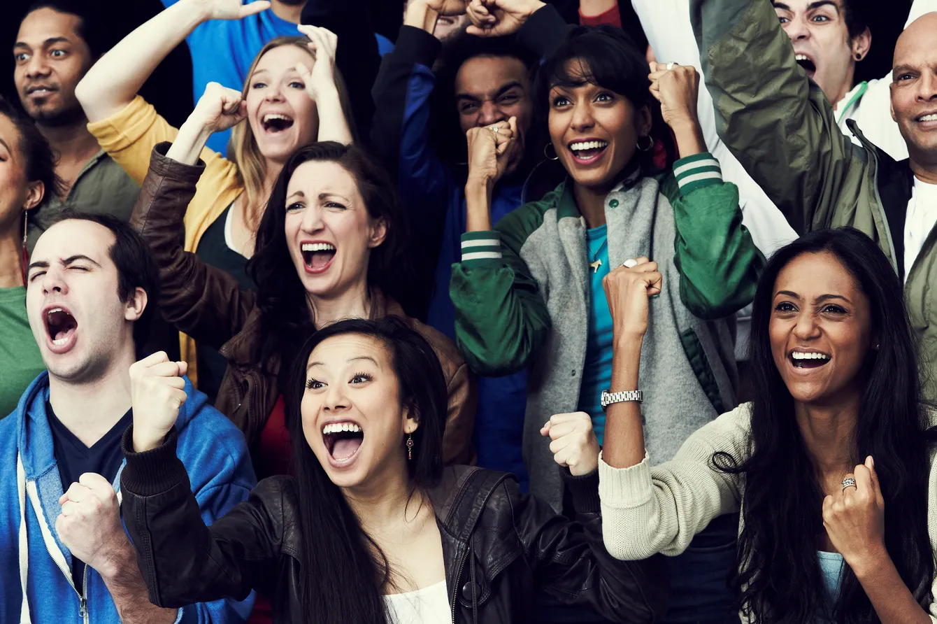 A crowd cheering with fists raised in the air — elation.